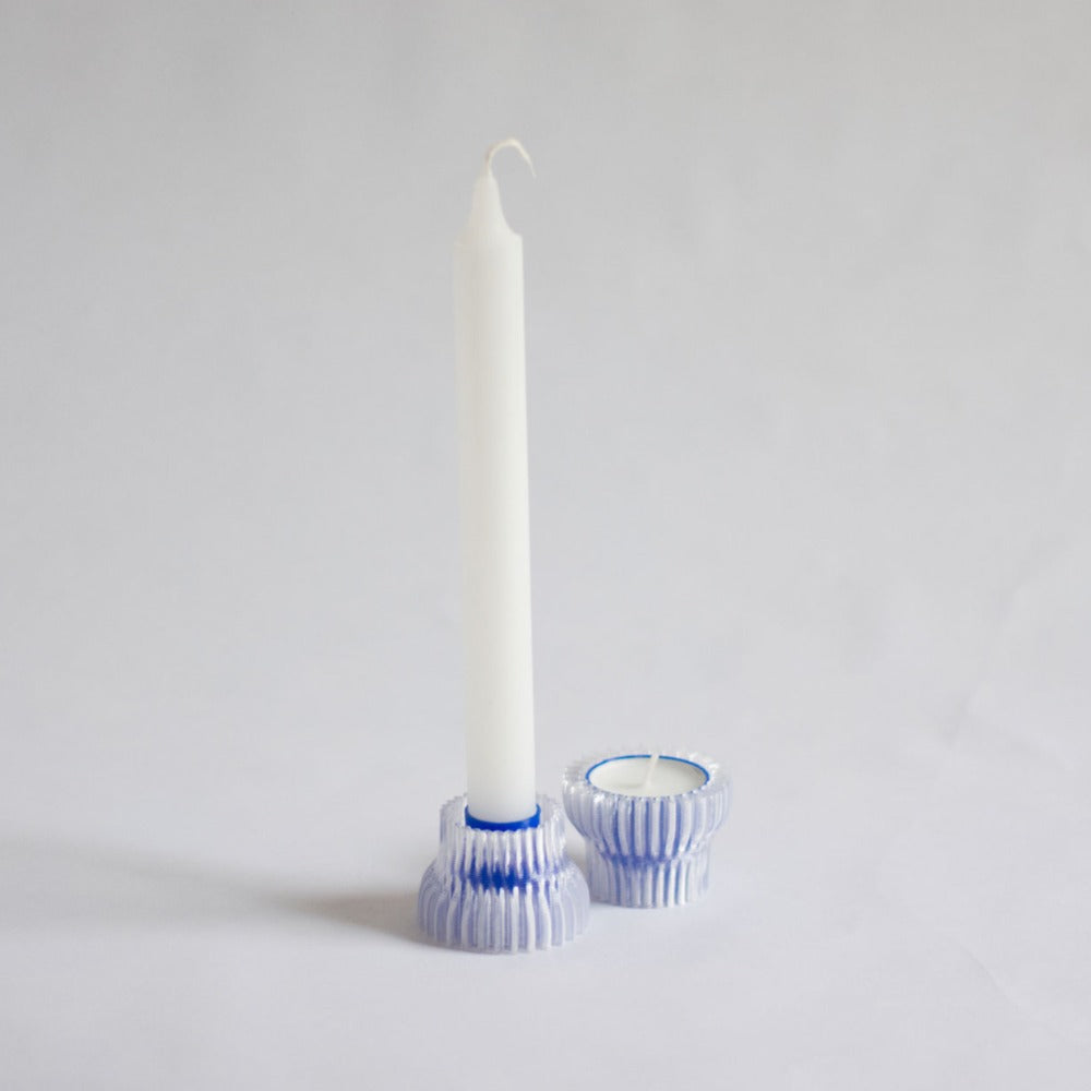 two blue and clear ribbed candle holders with white dinner candle and white tealight