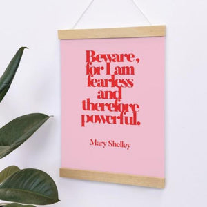 print with text 'beware, for i am fearless and therefore powerful' in red text on a pink background