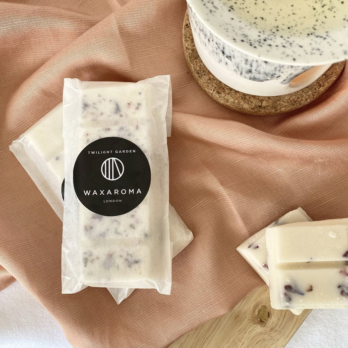 soy wax melt bar in wax paper packaging on a pink fabric background