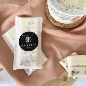 soy wax melt bar with petals in wax paper packaging on a pink fabric background